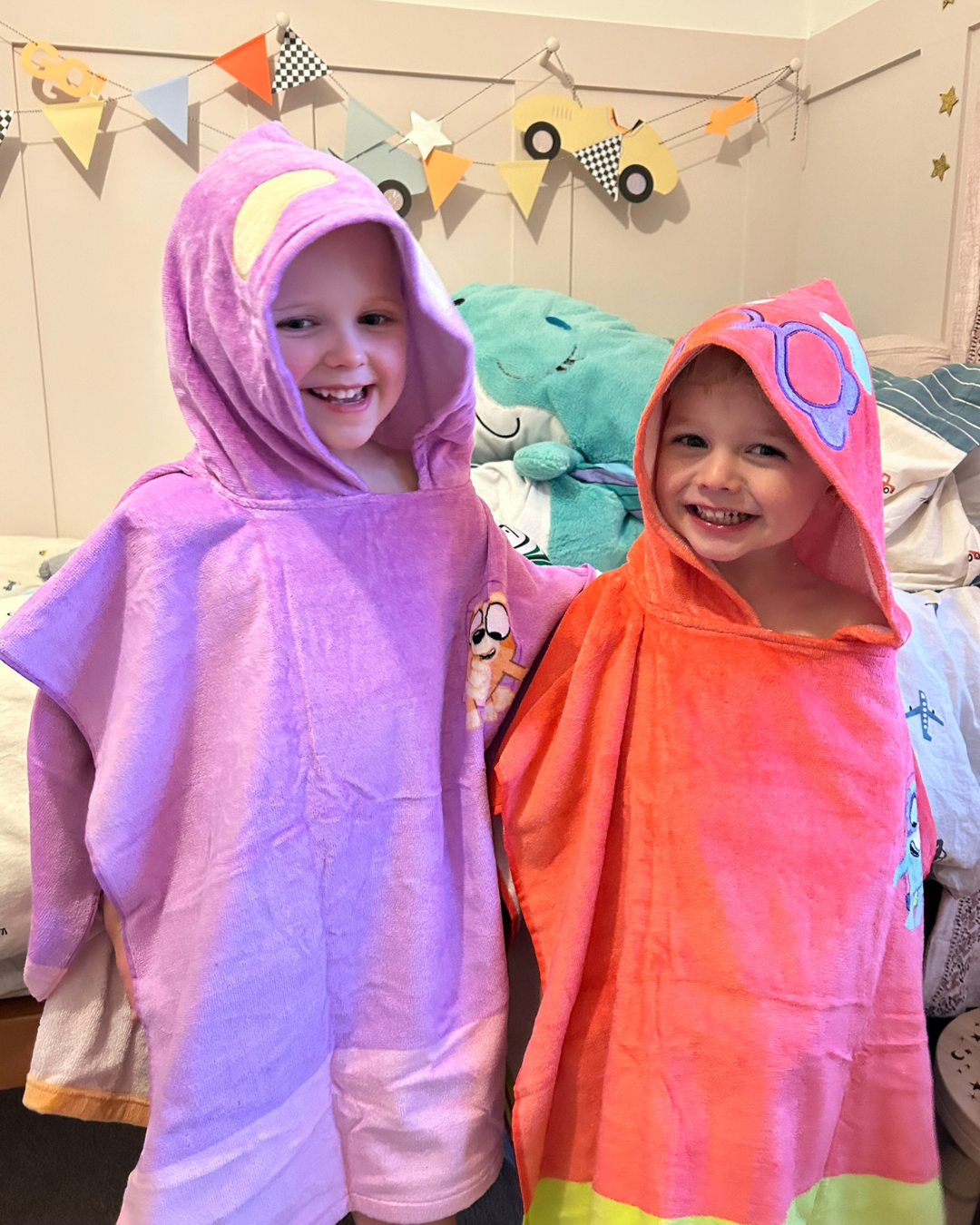 Two girls wearing Rita (Bingo) and Janet (Bluey) poncho towels