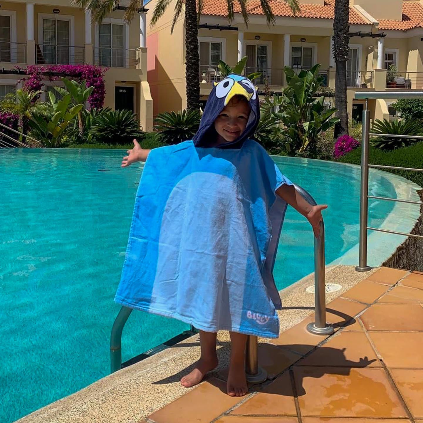 Boy at the pool side in Bluey poncho