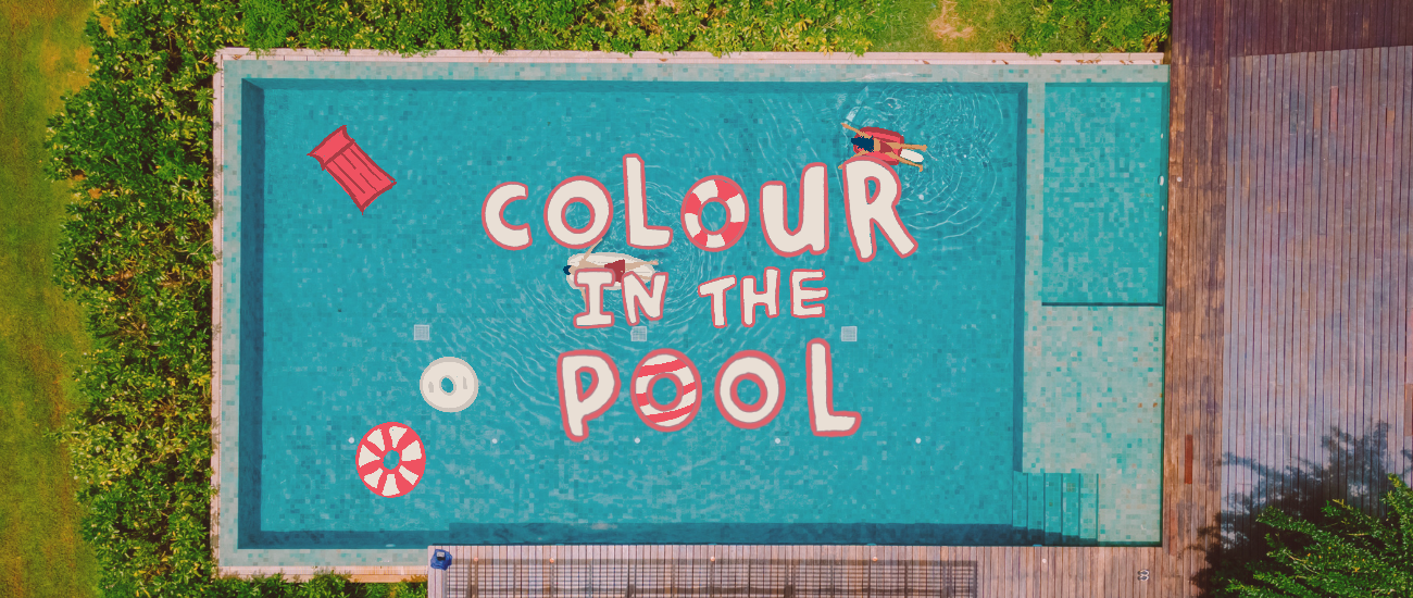 Pool from birds eye view with text "Colour in the pool". There are two people swimming on pool floats and a few pool floats dotted around the pool