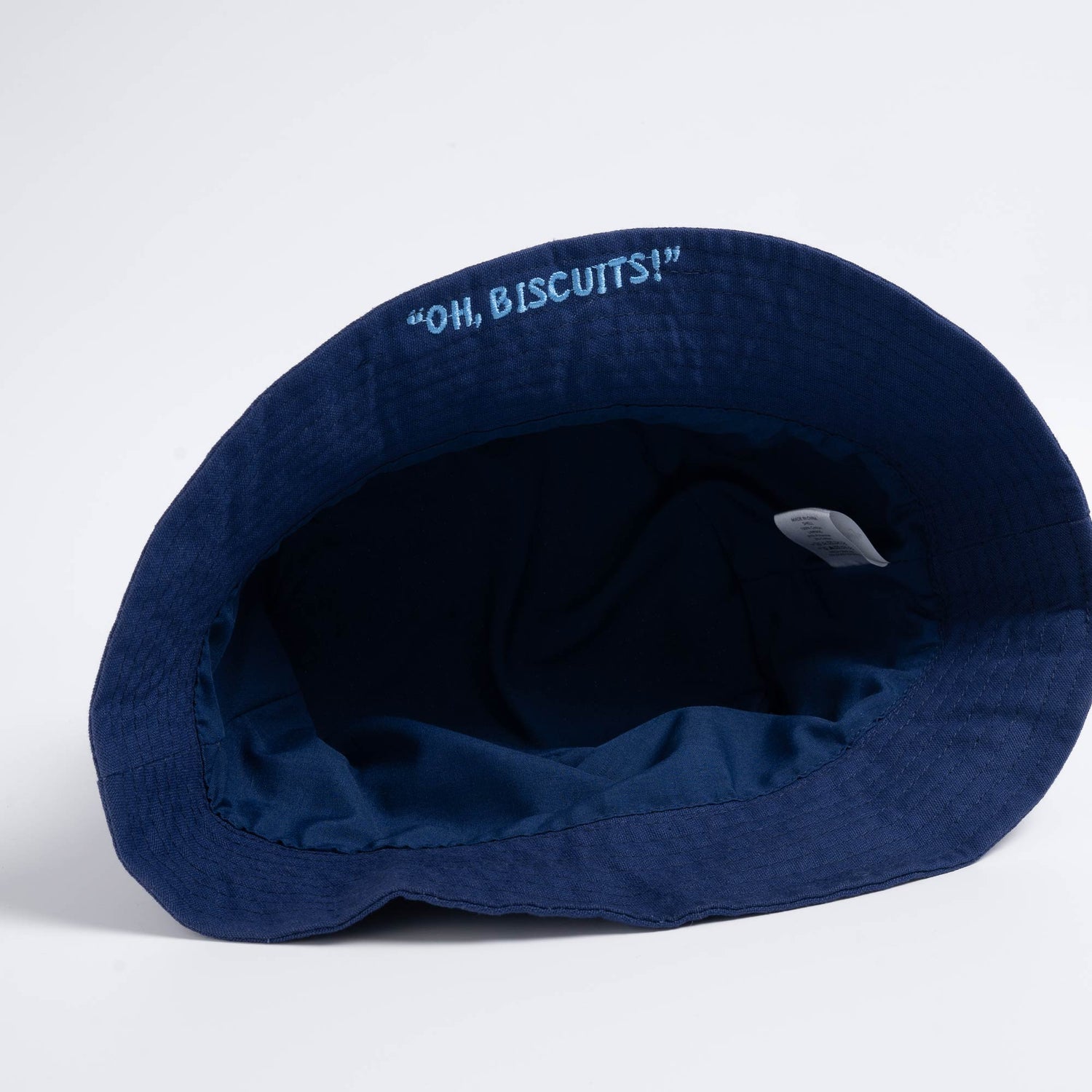Underside of the bucket hat showing embroidered rim slogan "Oh Biscuits!"