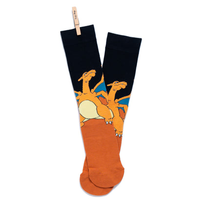 A pair of Pokémon Charizard crew socks hanging crossed and clipped together at the top by a small wooden peg
