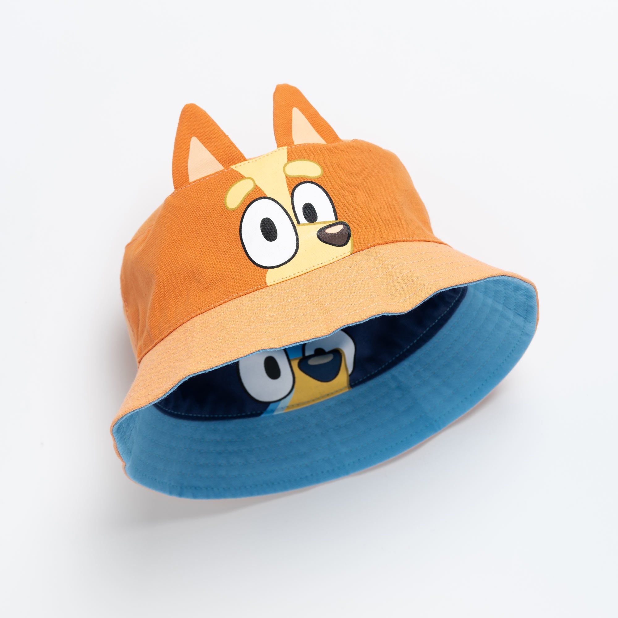 Tilted view of the kids reversible bucket hat showing the orange Bingo exterior and the blue Bluey interior