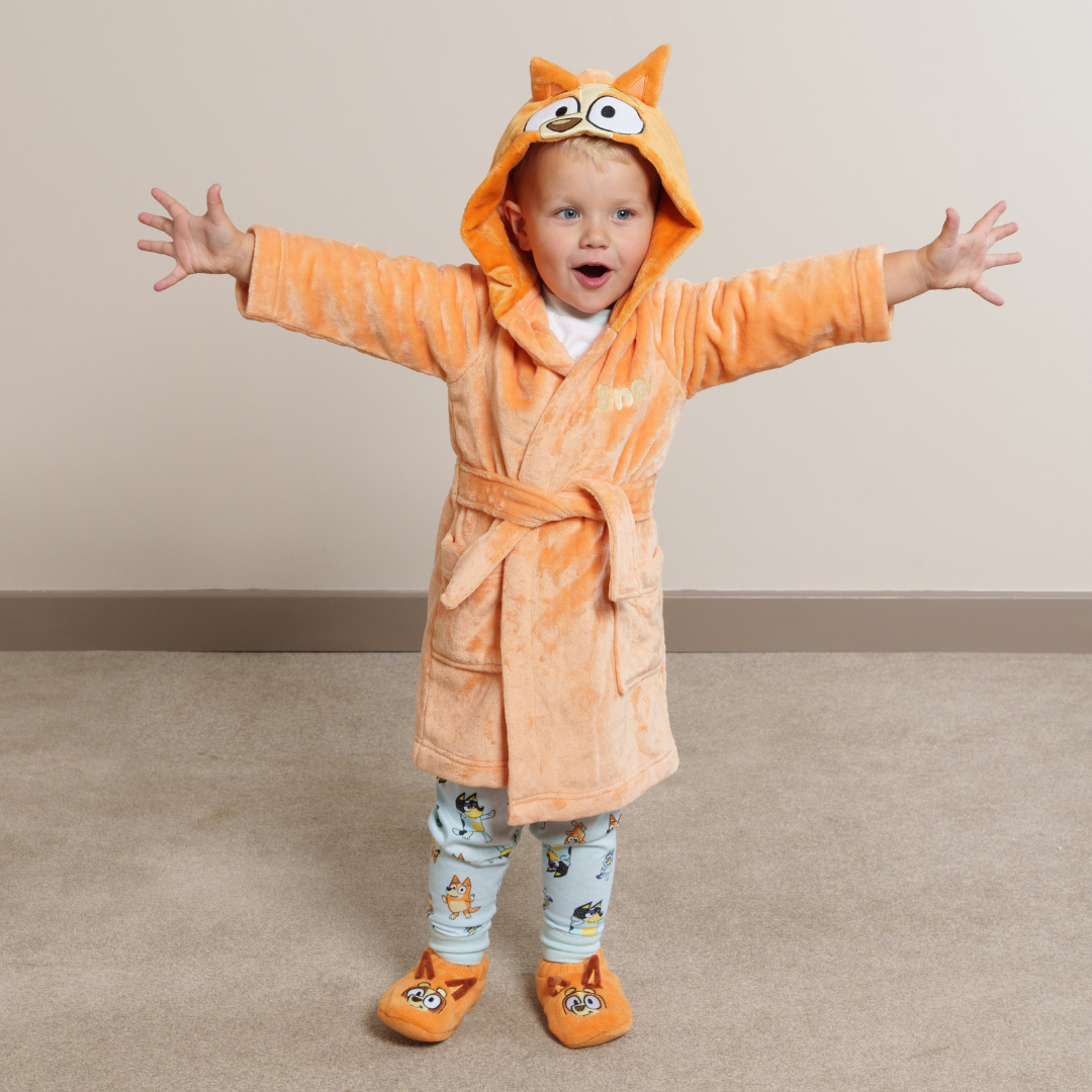 Child wearing Bingo dressinggown, matching Bingo slipper socks and Bluey fam jams