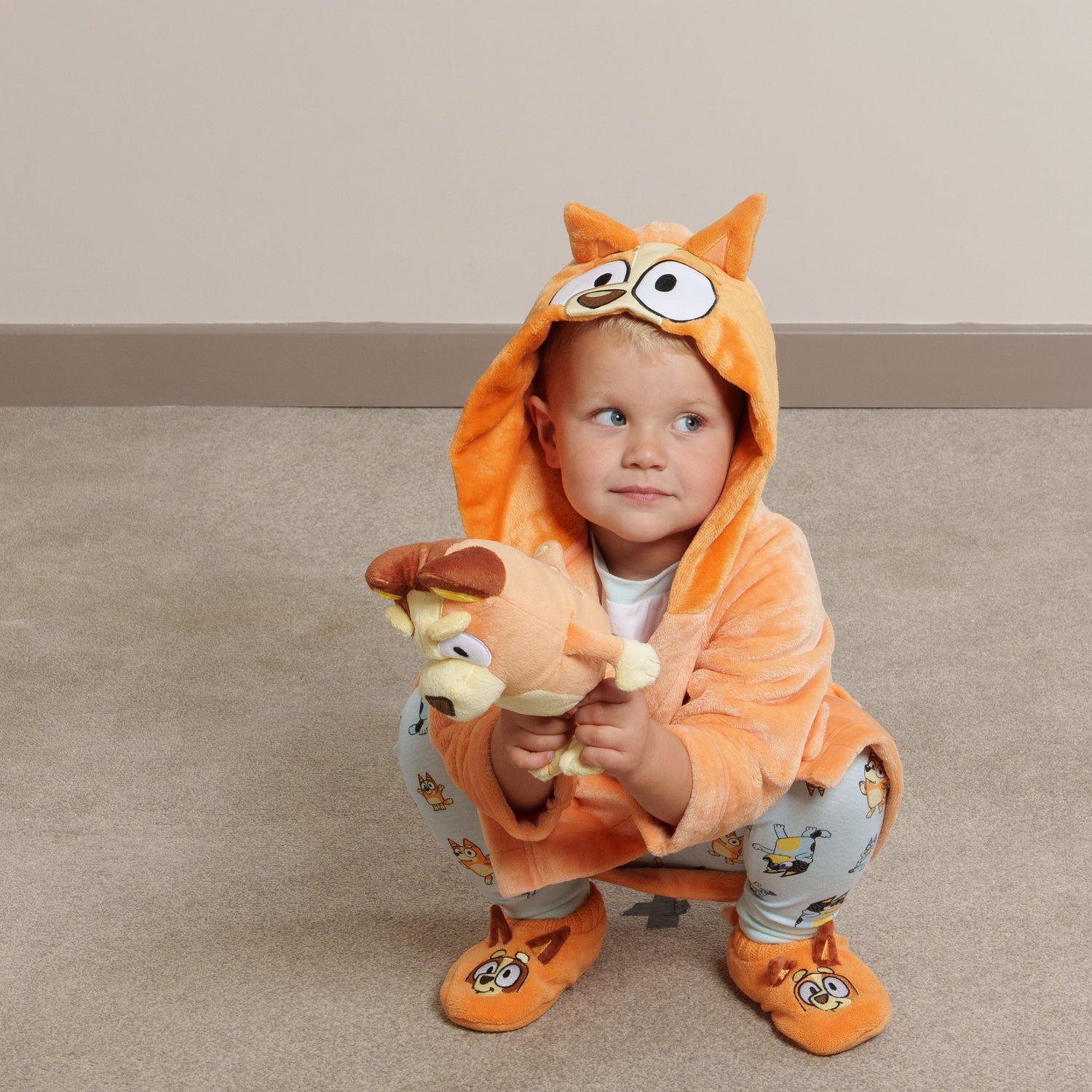Life style image of boy wearing Bingo dressing gown, matching Bingo slipper socks and Bluey fam jams