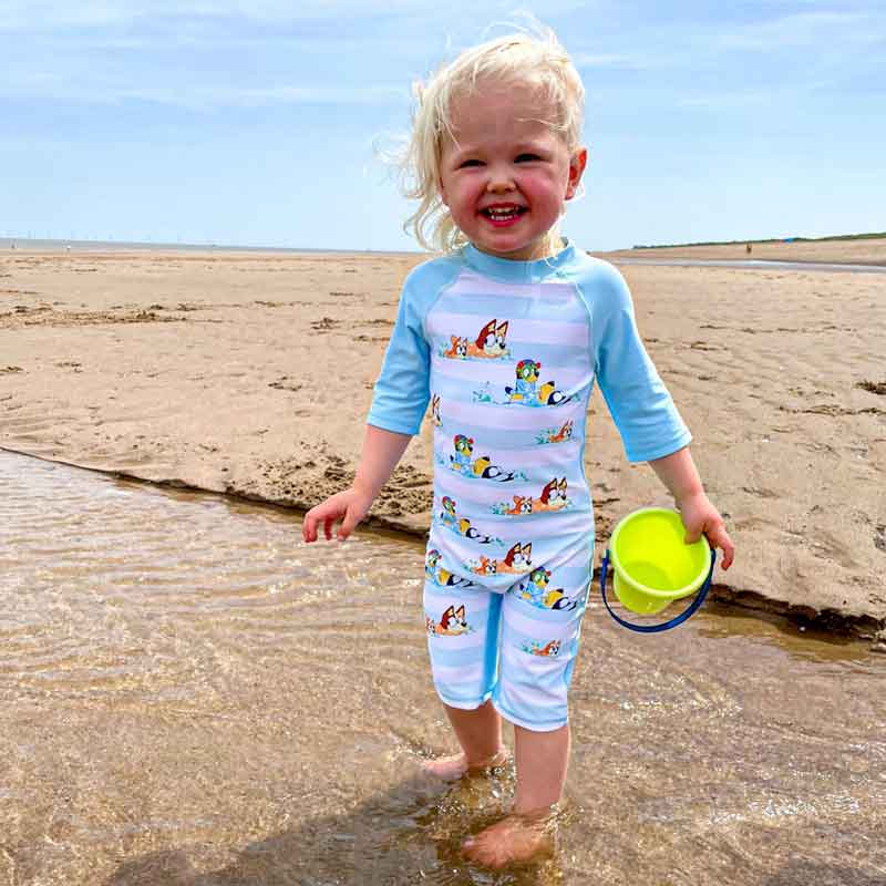 Girl at the beach in her Bluey Swimsuit
